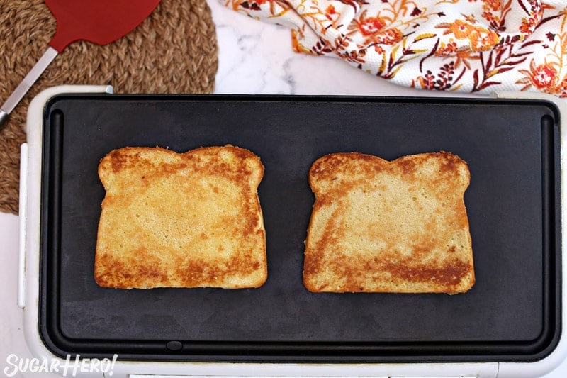 Two large pieces of French toast cake being toasted on a nonstick skillet