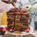 Close up of a French Toast Cake with a hand pouring maple syrup over it.