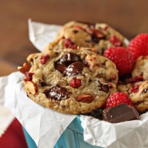 Close up of Raspberry Almond Chocolate Chunk Cookies in a light blue ceramic container.