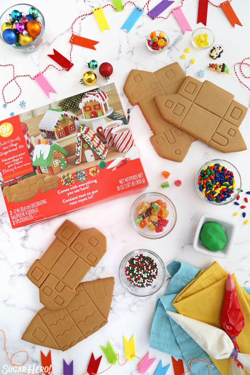 Overhead shot showing the ingredients for making gingerbread houses, including gingerbread, sprinkles, and royal icing