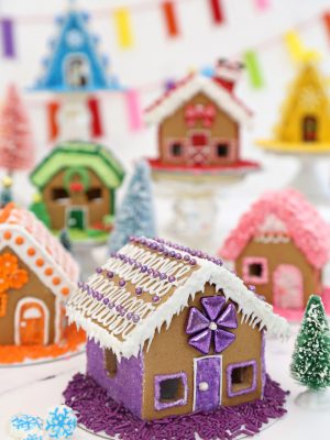 Miniature gingerbread houses decorated with rainbow colors | From SugarHero.com