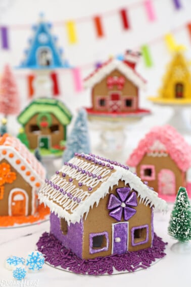 Miniature gingerbread houses decorated with rainbow colors | From SugarHero.com