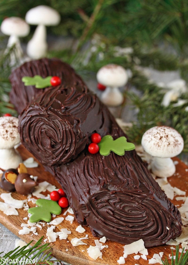Peanut Butter Cup Yule Log is made from a light chocolate sponge cake wrapped around a rich peanut butter filling and finished with a shiny chocolate glaze. | From SugarHero.com Peanut Butter Cup Yule Log - Straight shot of the yule log with fondant leaves, and meringue mushroom decoration. | From SugarHero.com