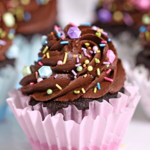Close up of a Chocolate Cupcake in a pink wrapper with more cupcakes in the background.