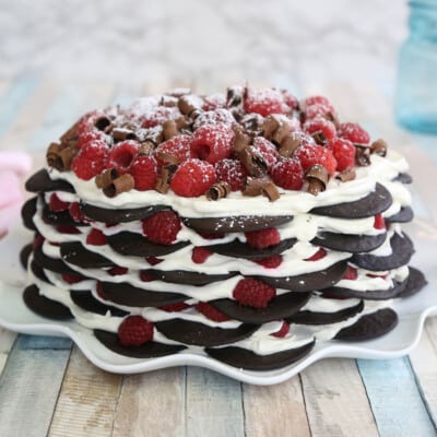 Close up of a Chocolate Raspberry No-Bake Cake on a white ruffled cake plate.