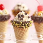 Four cannoli cones in an ice cream cone stand.