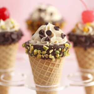 Four cannoli cones in an ice cream cone stand.
