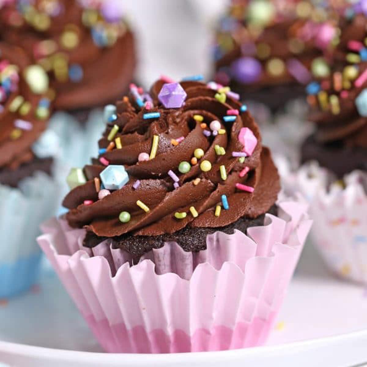 Close up of a Chocolate Cupcake in a pink wrapper with more cupcakes in the background.