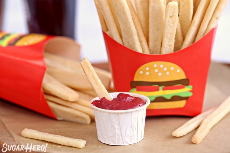 Close-up of a paper cup of frosting "ketchup" with a sugar cookie french fry sticking out the top