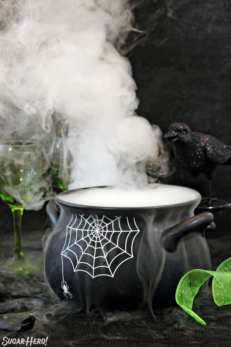 Black cauldron with a spiderweb pattern and smoke coming out the top