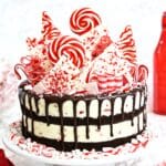 Candy Cane Mousse Cake on a white cake plate surrounded by crushed candy canes.