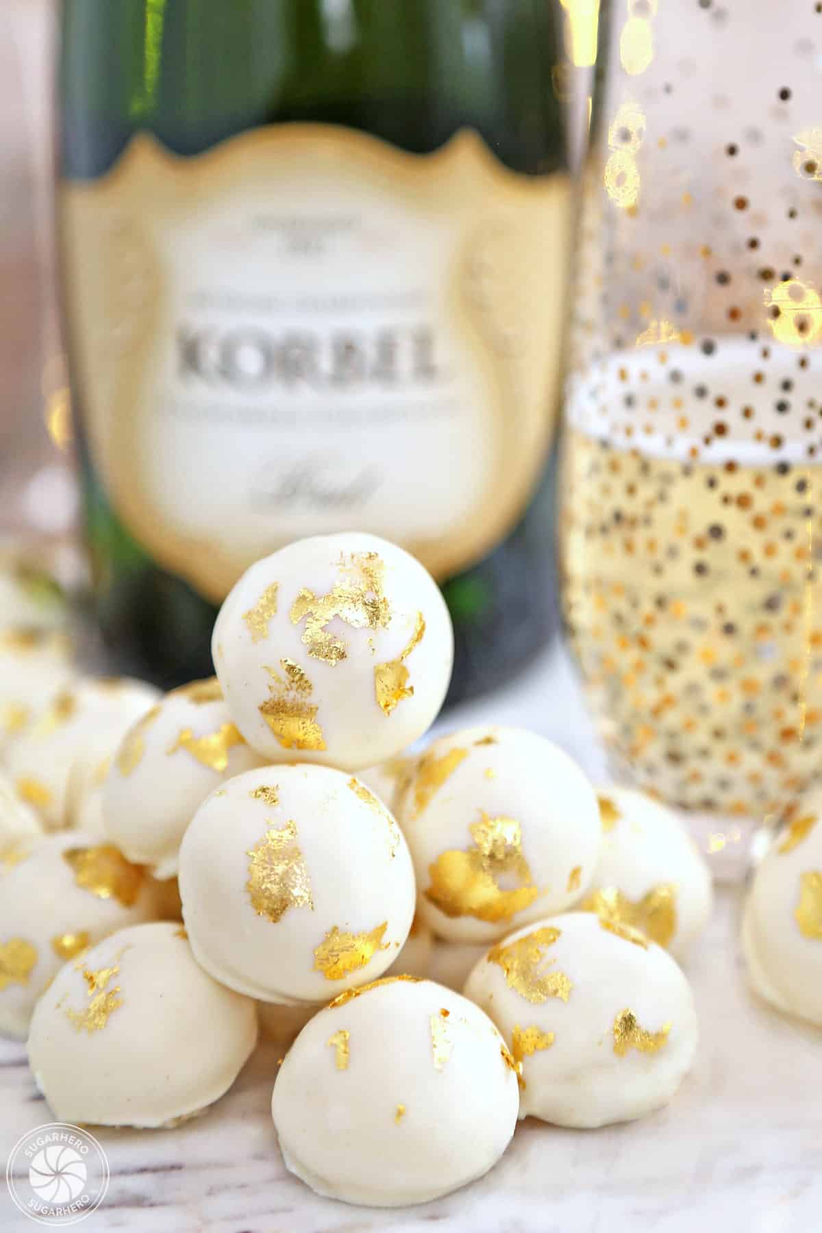 Champagne White Chocolate Truffles in a pile in front of a bottle of champagne