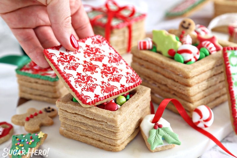 Hand placing and red and white decorated cookie lid on an Edible Christmas Cookie Box