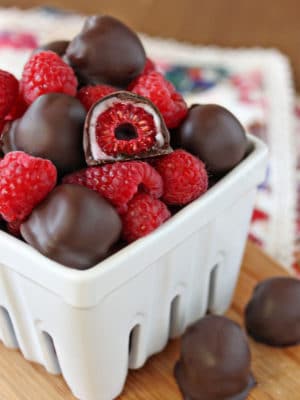 White ceramic container with chocolate-covered raspberries piled up