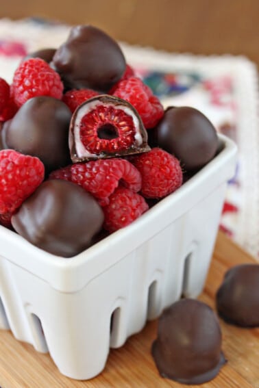 White ceramic container with chocolate-covered raspberries piled up