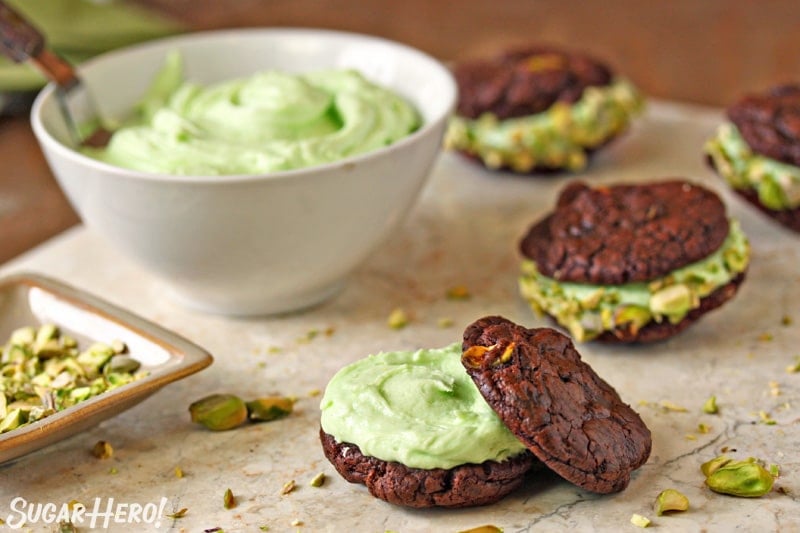 Chocolate Pistachio Sandwich Cookie being assembled with a bowl of pistachio frosting in the background