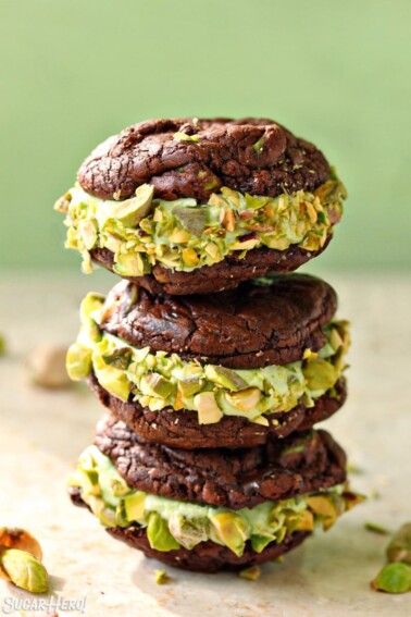 Stack of 3 Chocolate Pistachio Sandwich Cookies in front of a green background.