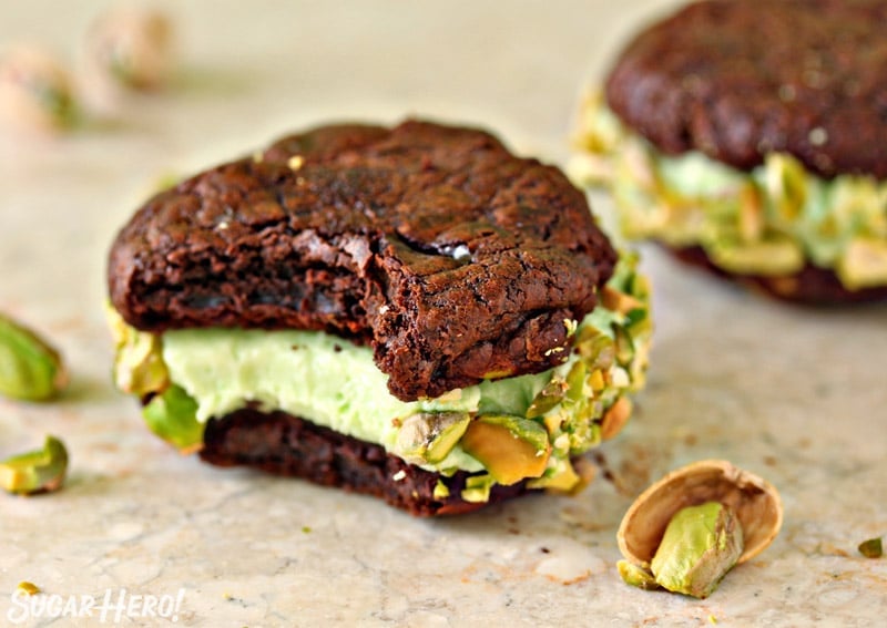 Chocolate Pistachio Sandwich Cookie on a marble board with a bite taken out of it