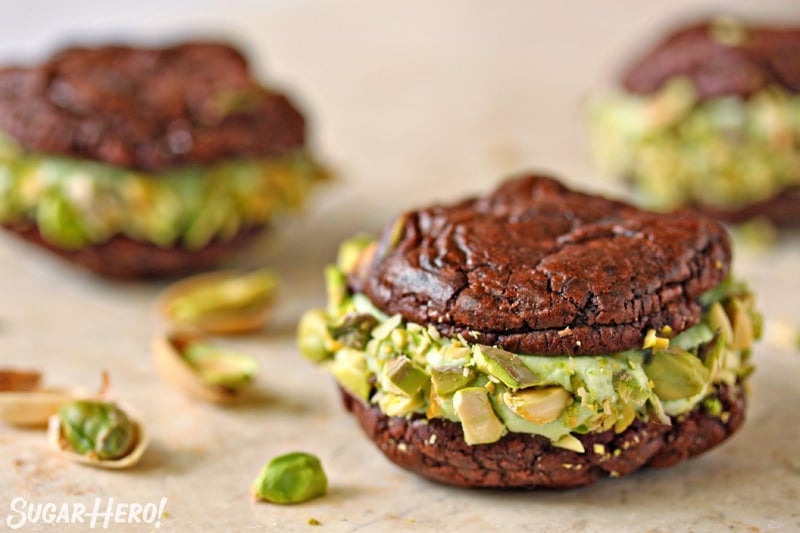 Chocolate Pistachio Sandwich Cookie on a marble board with pistachios scattered around