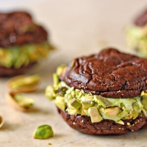 Chocolate Pistachio Sandwich Cookie on a marble board with pistachios scattered around