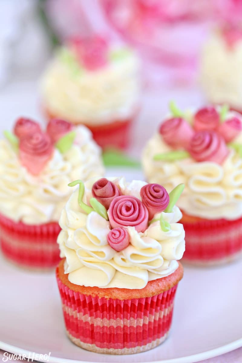 Group of pink cupcakes with white frosting and pink fondant flowers