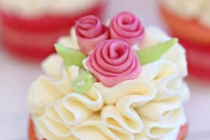 Photo of frosted cupcake with fondant flowers and text overlay for Pinterest