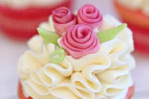 Photo of frosted cupcake with fondant flowers and text overlay for Pinterest