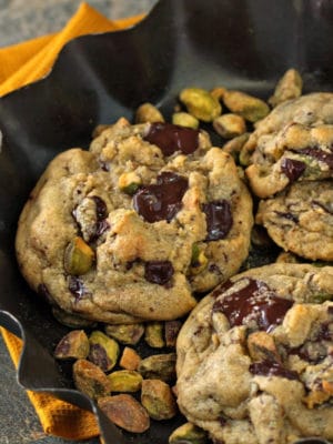 Pistachio Chocolate Chunk Cookies in a fluted dish of pistachios
