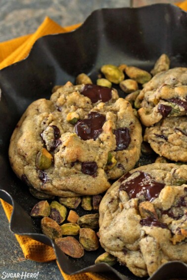 Pistachio Chocolate Chunk Cookies in a fluted dish of pistachios