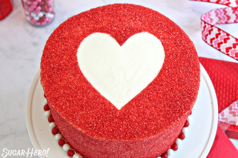 Cake covered with red sparkling sugar, with an empty white space in the center in the shape of a heart