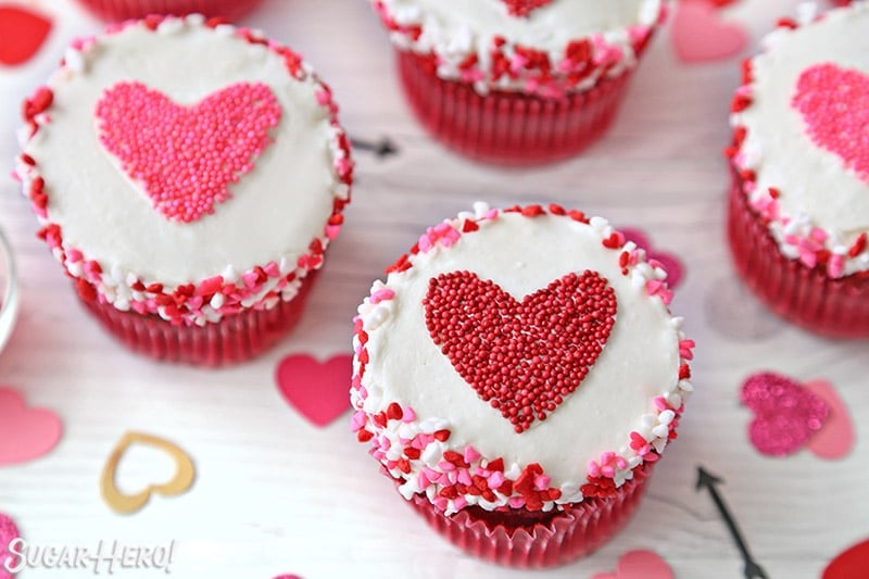 White cupcake with a red heart-shaped sprinkle shape in the center