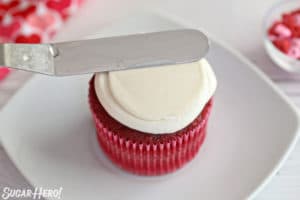 Small spatula smoothing the top of a cupcake with white buttercream