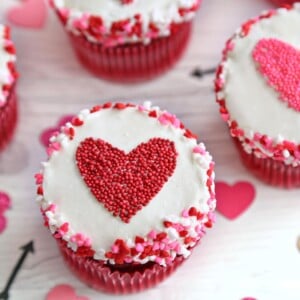 Close-up of a cupcake with a red heart-shaped sprinkle shape in the center.