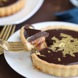 Baileys Chocolate Caramel Tart on a white plate with caramel dripping out