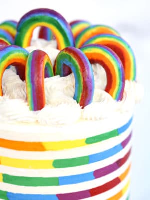 Buttercream Rainbows arranged in a circle on top of a rainbow-striped cake