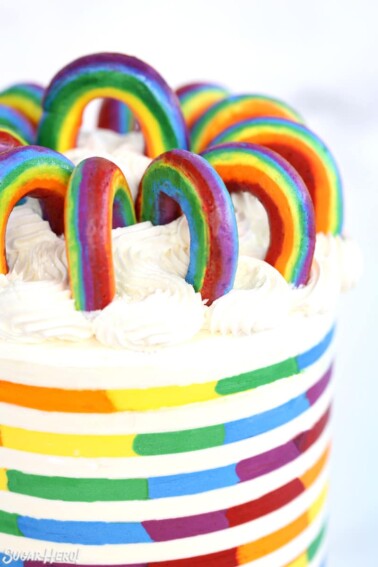 Buttercream Rainbows arranged in a circle on top of a rainbow-striped cake