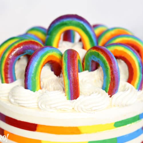 Buttercream Rainbows in a circle on top of a rainbow striped cake