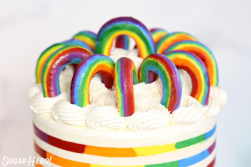 Buttercream Rainbows in a circle on top of a rainbow striped cake
