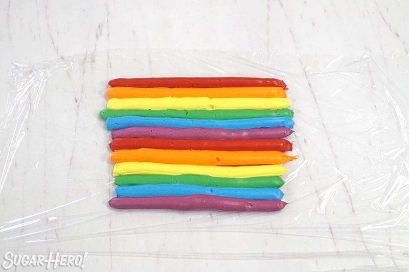 Two rows of rainbow buttercream on plastic wrap