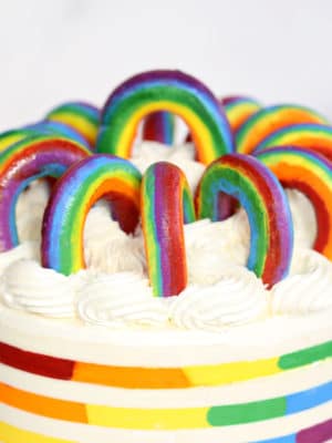 Close-up of Buttercream Rainbows on top of a rainbow striped cake