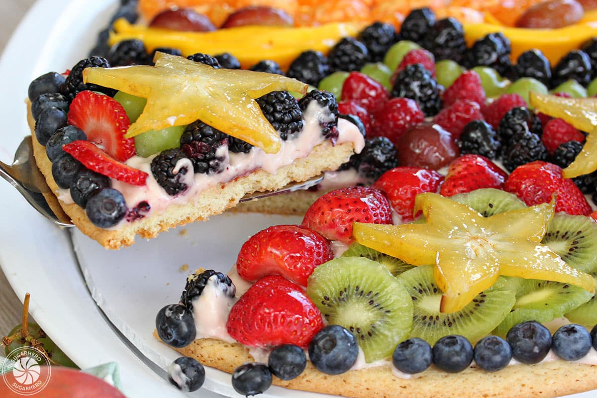 Cake server lifting out a slice of Easter Egg Fruit Pizza