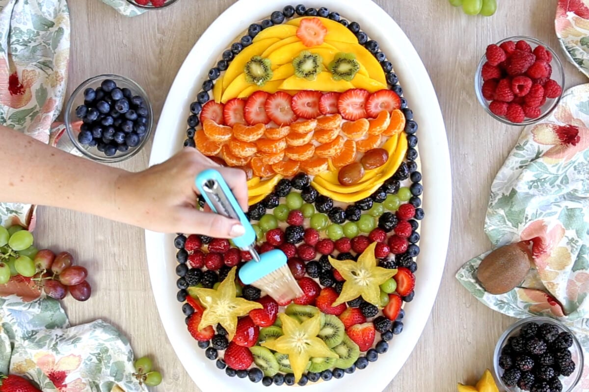 Brushing apricot glaze on the cut fruit on the fruit pizza