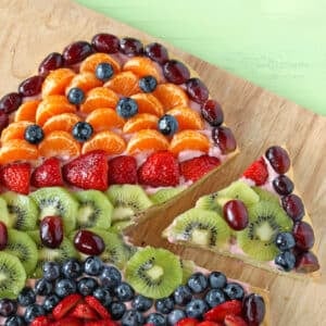 Easter Fruit Pizza on a wooden cutting board with a slice removed.