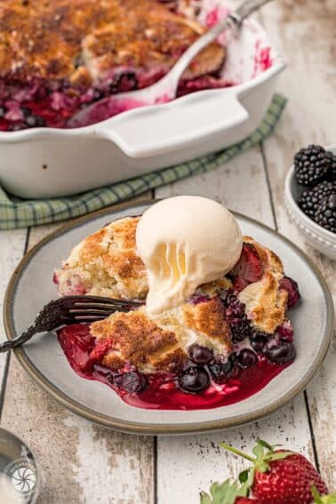 Berry cobbler on a plate with a scoop of ice cream on top