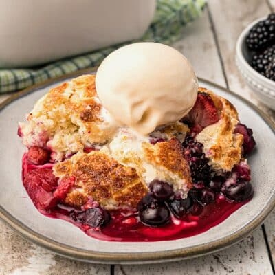 Close up of a single serving of Mixed Berry Cobbler with a scoop of ice cream on top.
