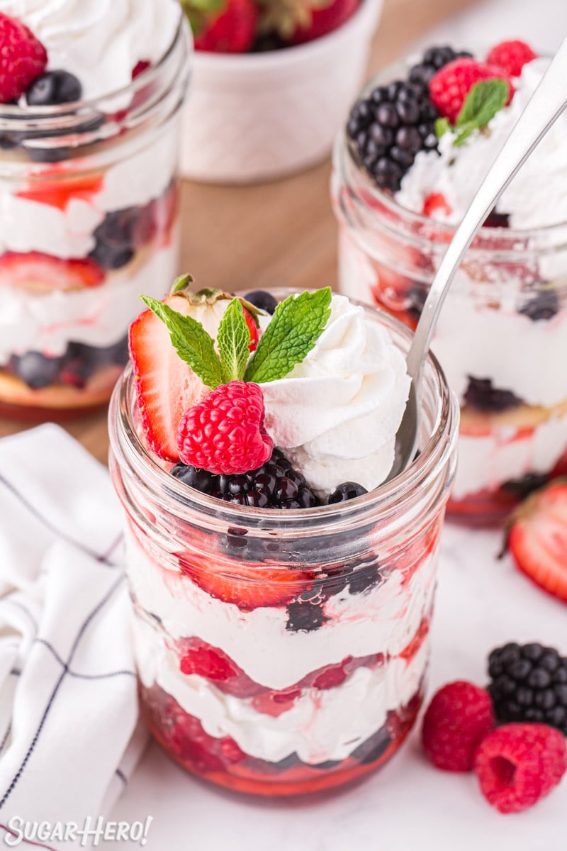 Mixed Berry Shortcakes in mason jars with a spoon sticking out of one