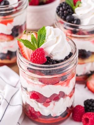 Mixed berry shortcake in a jar with berries, whipped cream, and shortcakes