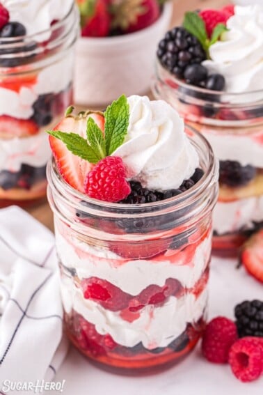 Mixed berry shortcake in a jar with berries, whipped cream, and shortcakes