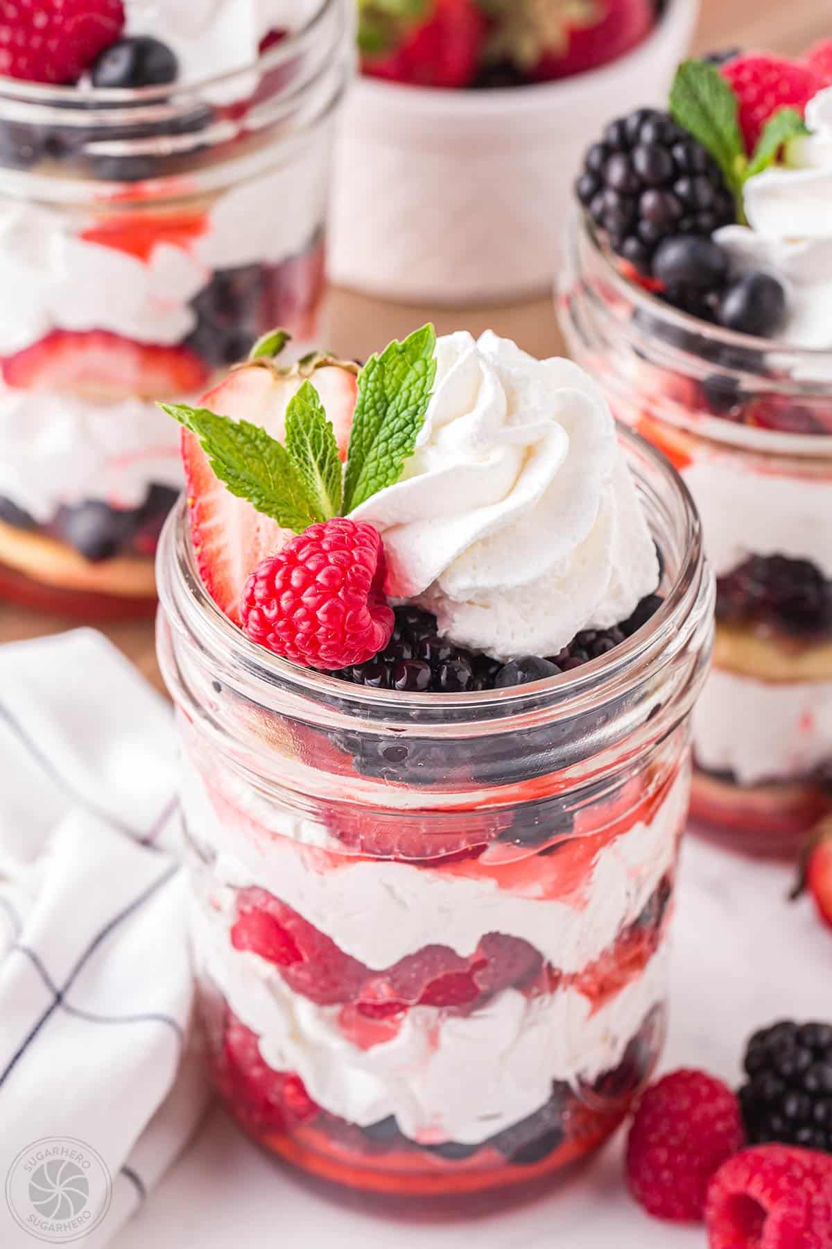 Mixed berry shortcake in a jar with berries, whipped cream, and shortcakes