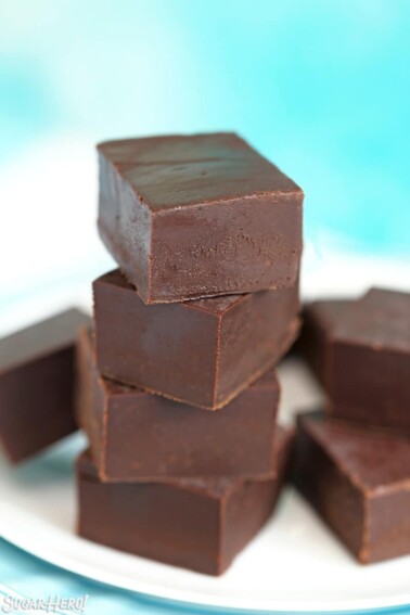 Stack of chocolate fudge pieces on a white plate.